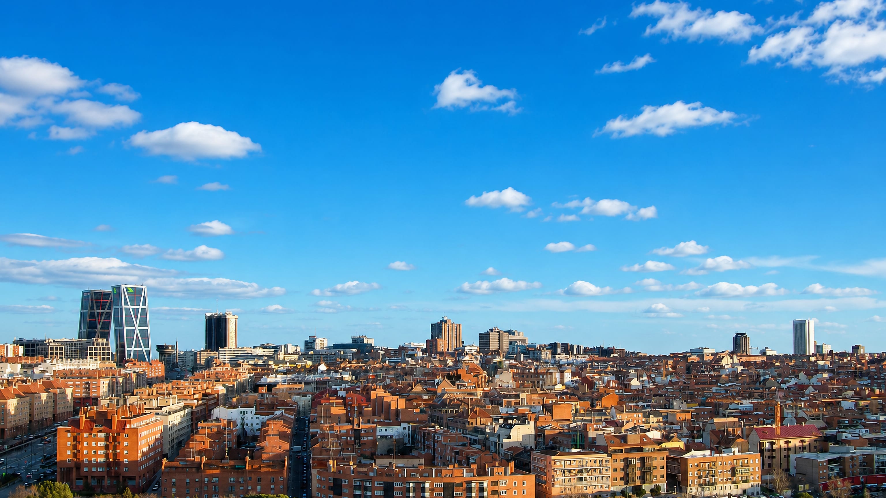 Wide daytime view of Madrid's Valdeacederas district with red-tiled rooftops and the leaning KIO Towers at Plaza de Castilla.
