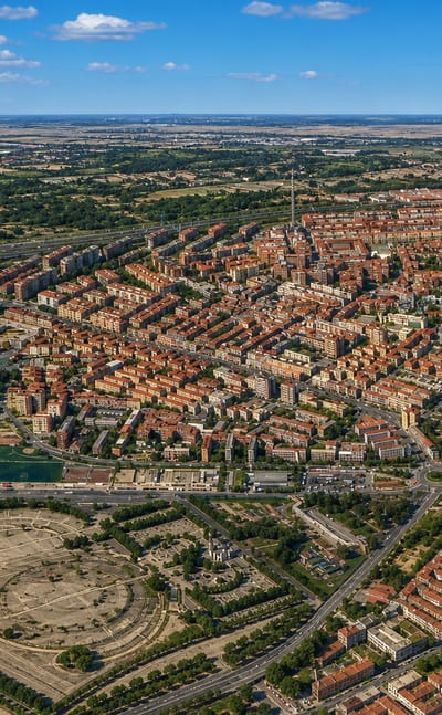 High aerial view over Ventas's dense red-roofed streets and green spaces in eastern Madrid