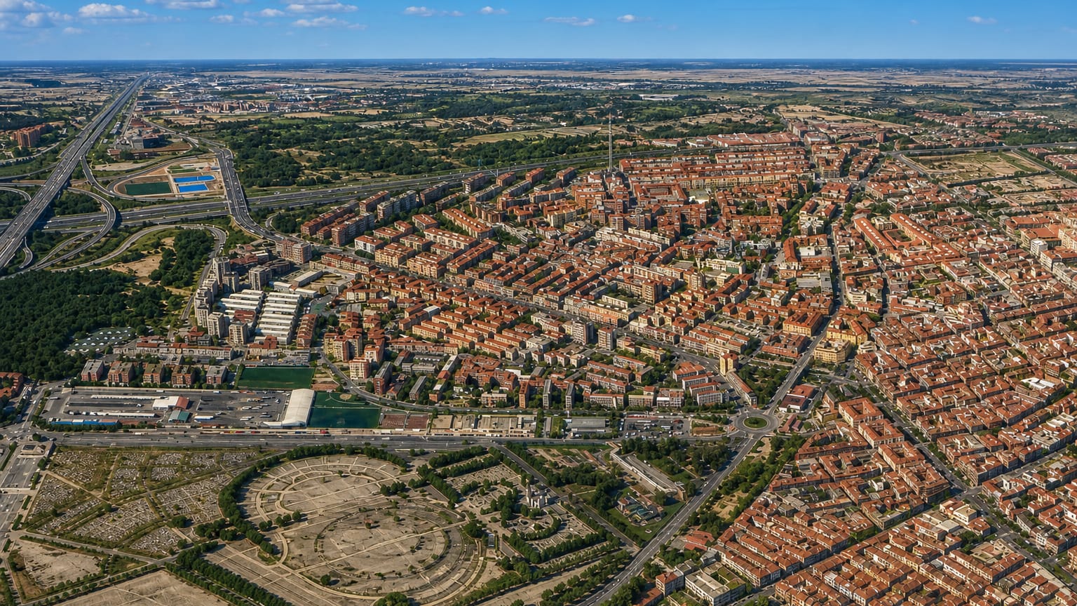 High aerial view over Ventas's dense red-roofed streets and green spaces in eastern Madrid
