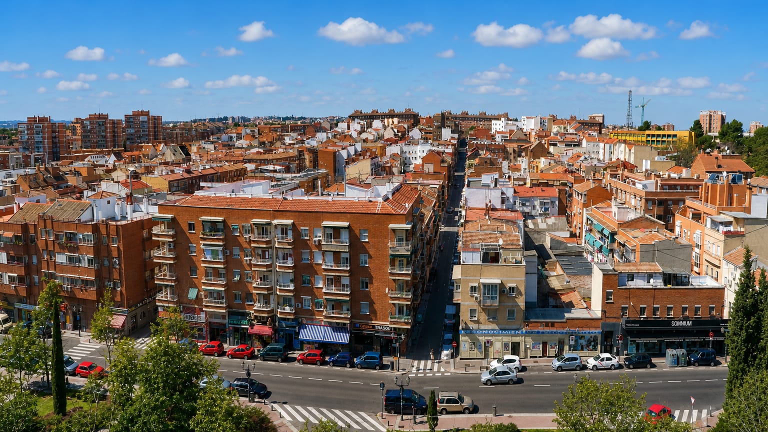 Elevated view over dense red-brick apartment blocks and a busy avenue in Madrid's Zofío barrio