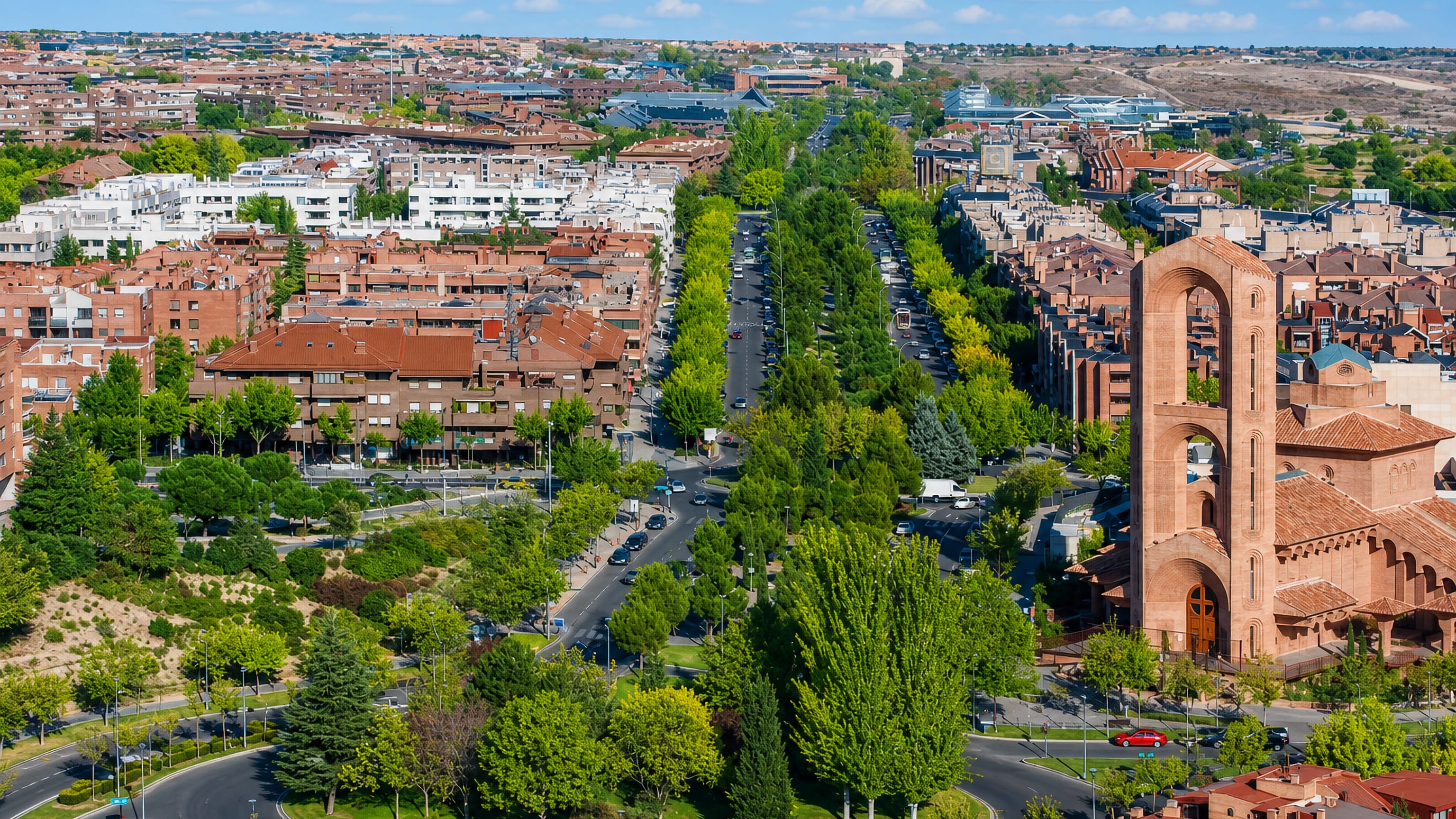 Aerial of Pozuelo de Alarcon, Madrid, with brick housing, a tree-lined avenue and the parish church tower.