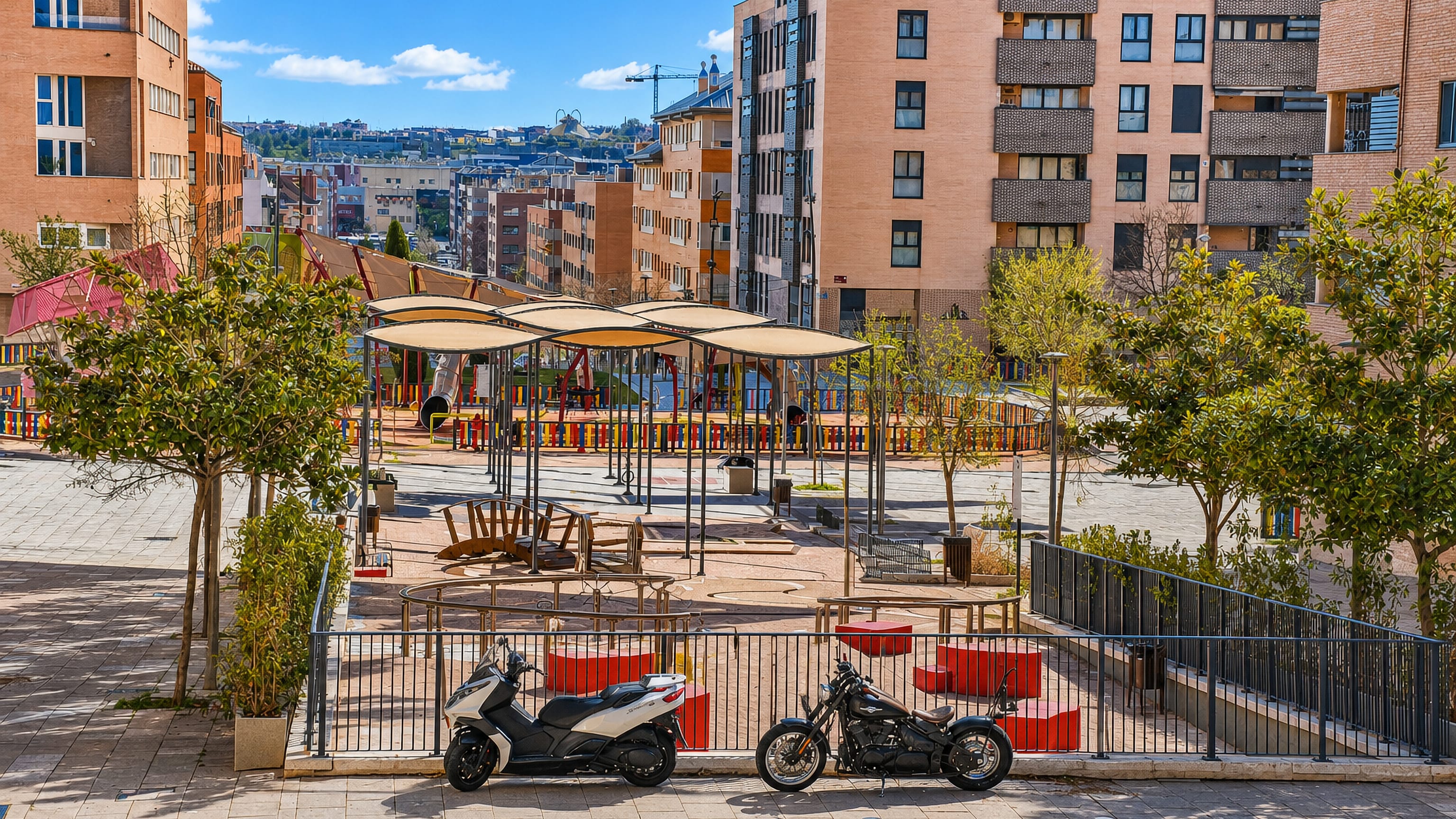 Brick apartment blocks around a shaded playground square in San Sebastian de los Reyes, north of Madrid.
