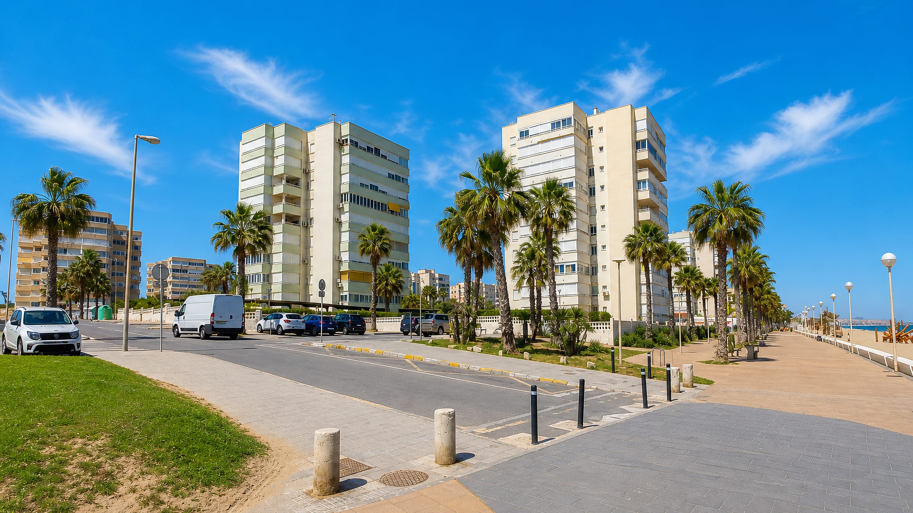 Palm-lined seafront promenade and white apartment blocks beside the beach at Urbanova, Alicante.