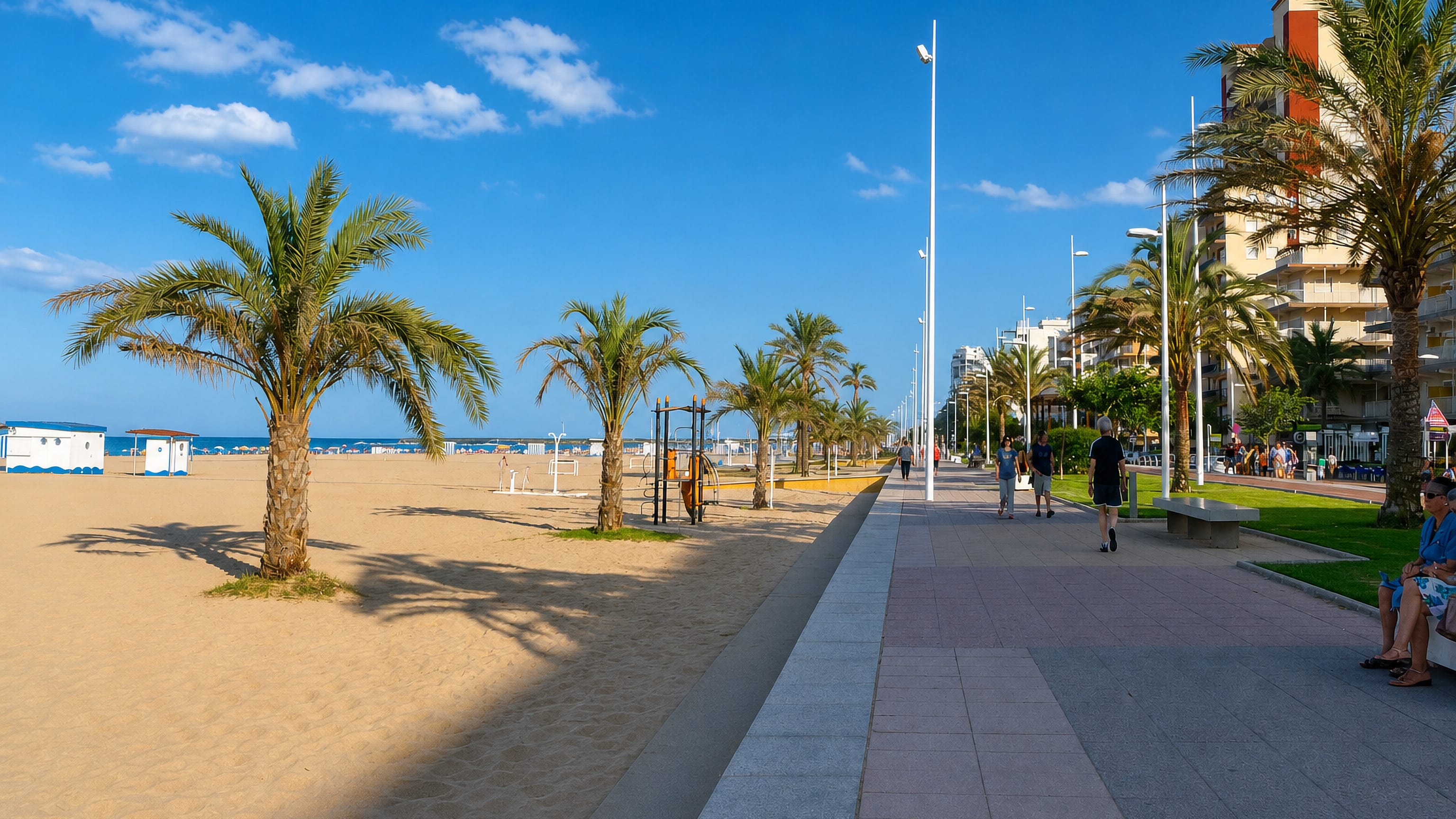 Palm-lined seafront promenade and wide sandy beach at Platja de Gandia on Spain's Valencian coast.