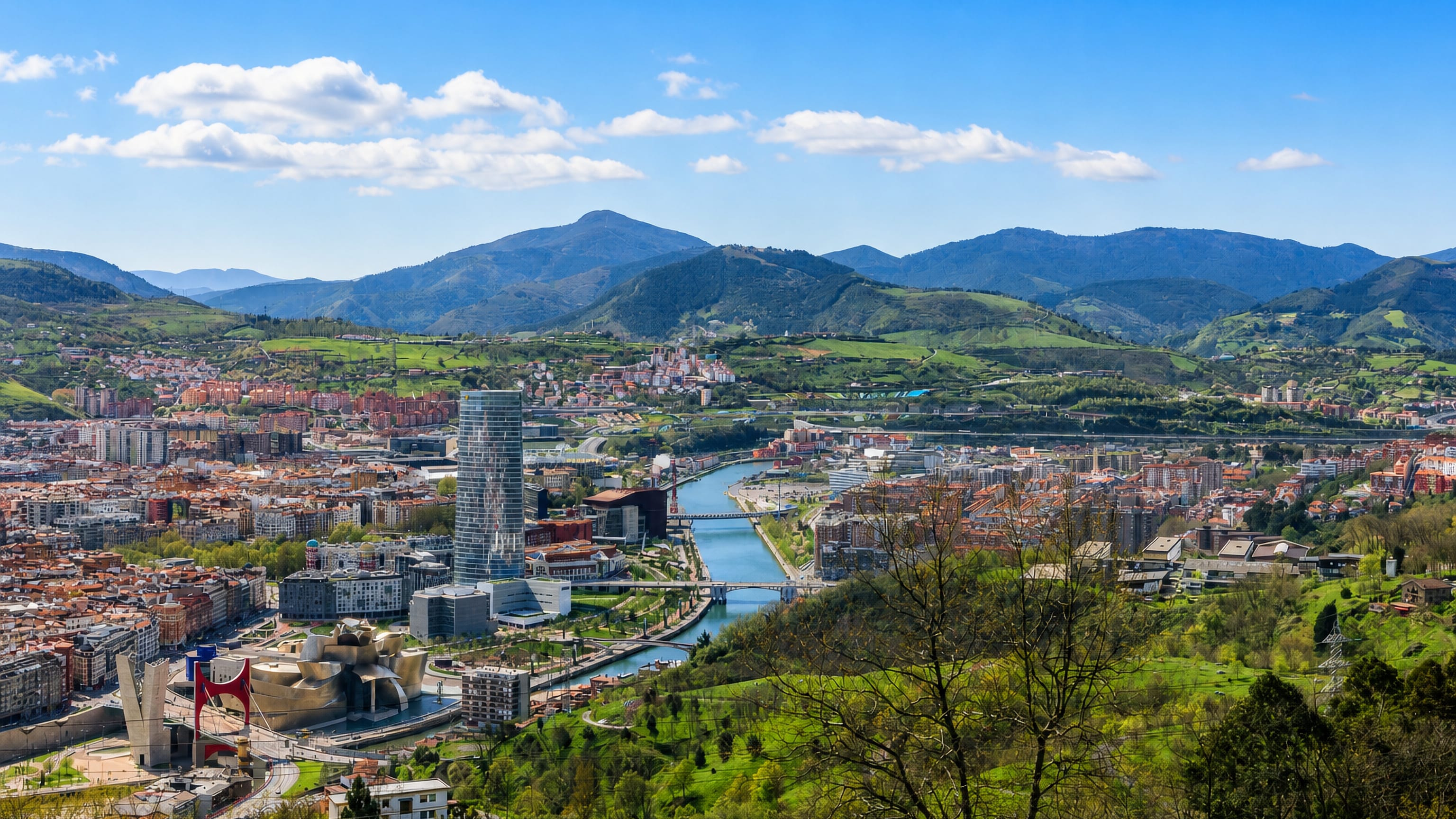 Bilbao's Guggenheim Museum, the red La Salve arch and Torre Iberdrola along the Nervión river, seen from the hills