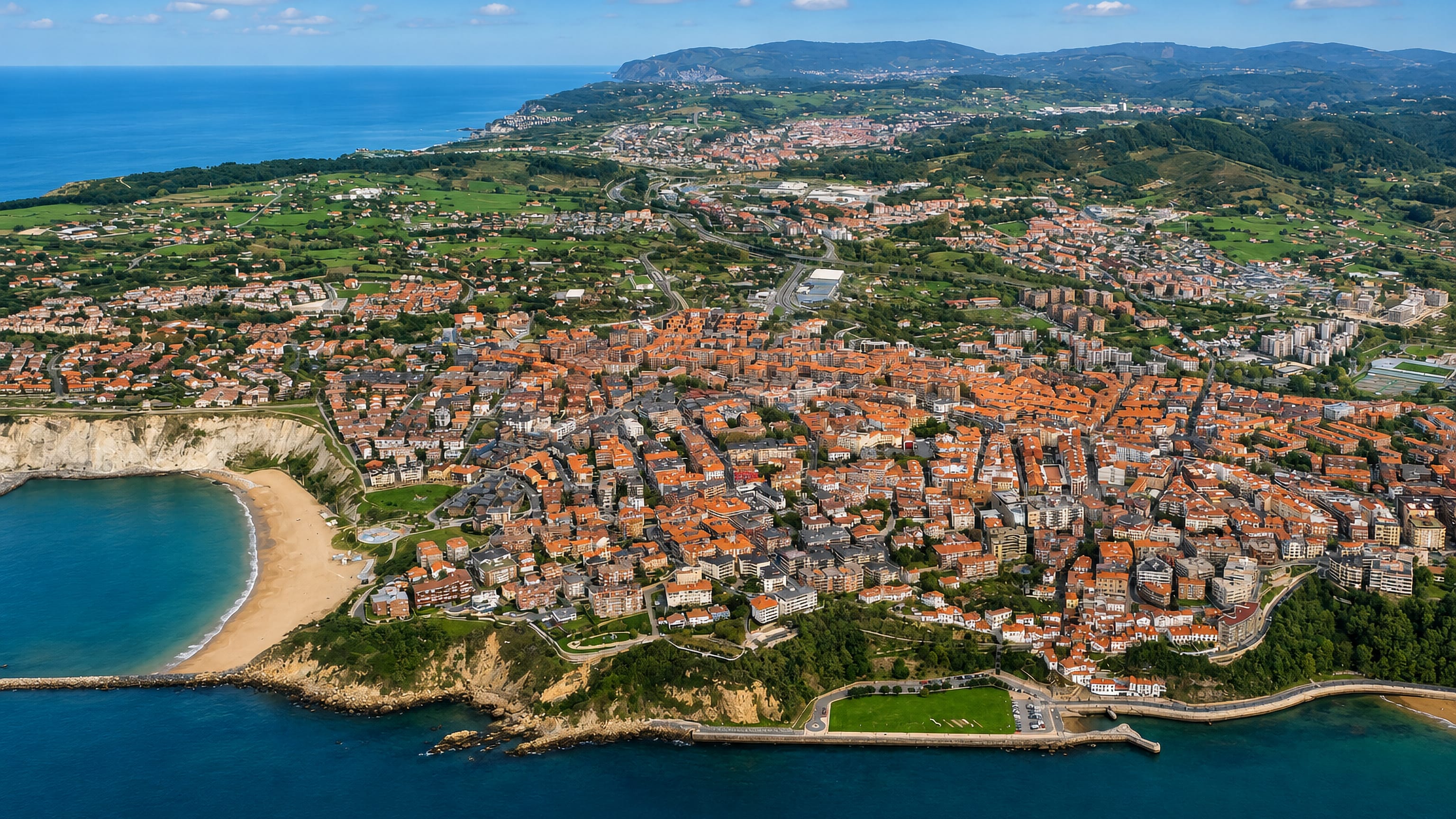 Aerial view of red-roofed Algorta above its cliff-backed cove beach on the Getxo coast, Biscay.