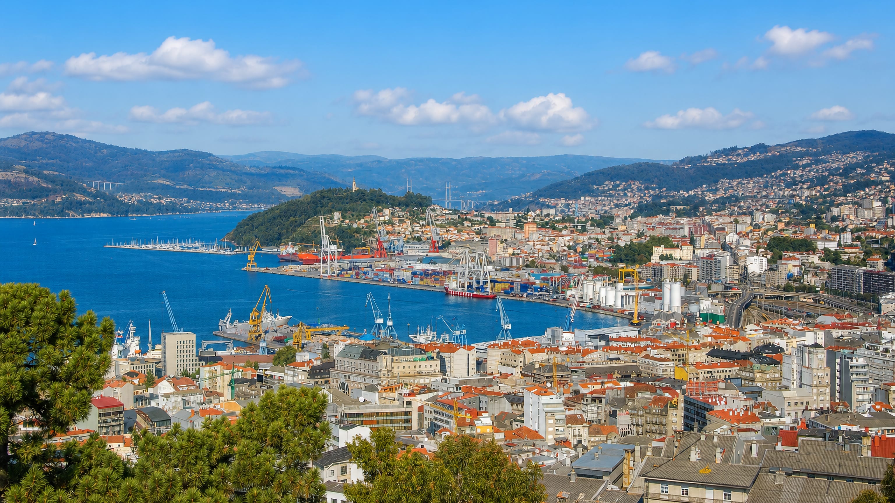 Vigo's port cranes, container quays and city rooftops along the blue Ría de Vigo, with green hills beyond.