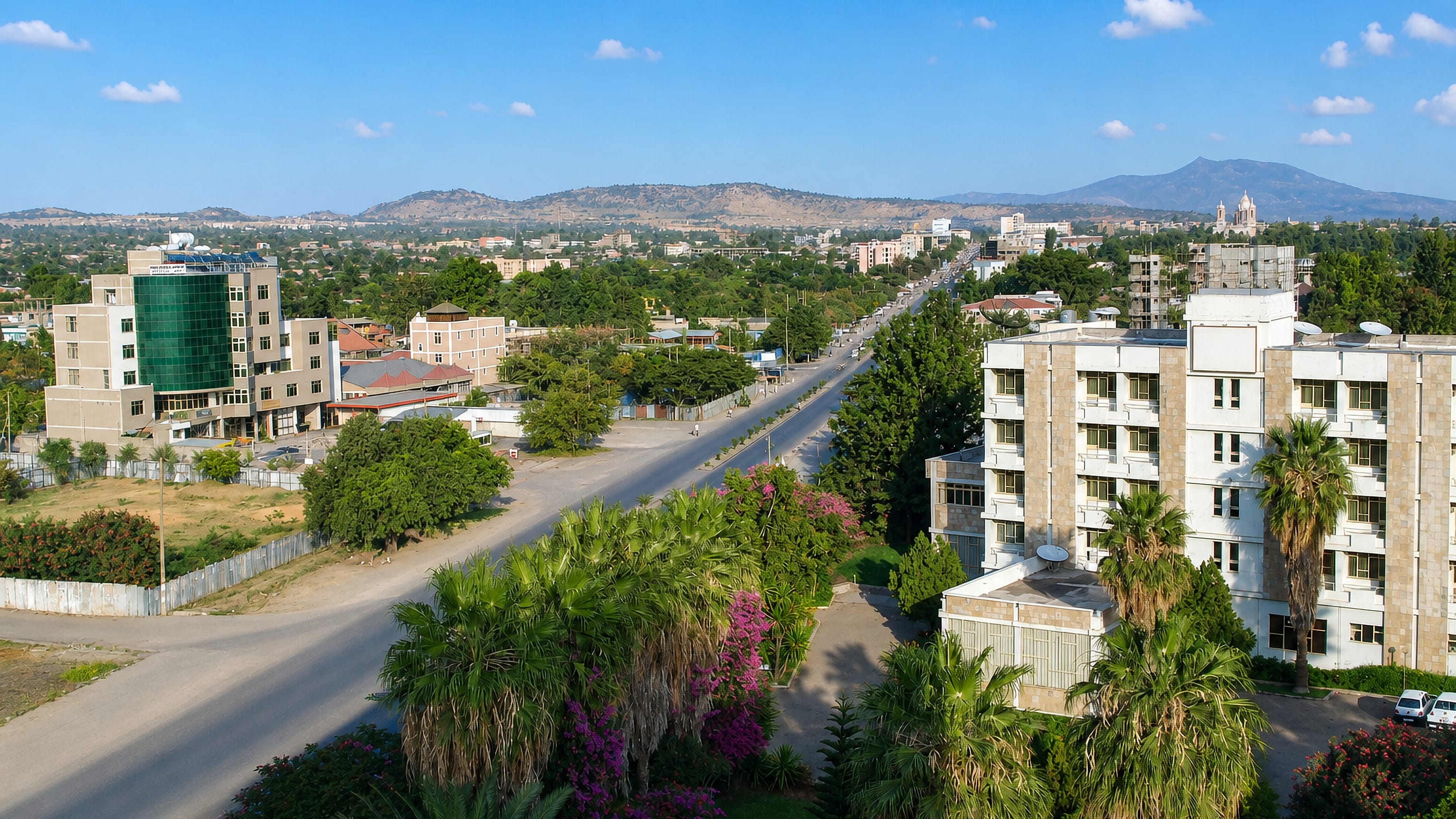 Wide palm-lined avenue and mid-rise buildings in Nazrēt (Adama), Ethiopia, with Rift Valley hills beyond.