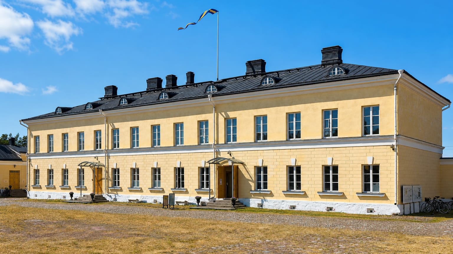 The yellow neoclassical Eckerö Post and Customs House under a blue sky, Åland, Finland.