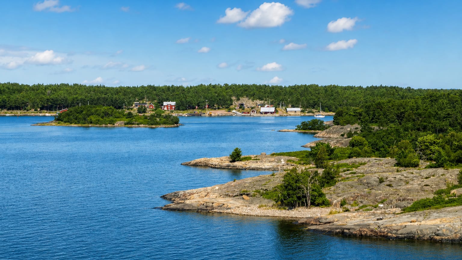 Sottunga, Åland: rocky pine-clad islets and blue water with red and white village houses across the bay.