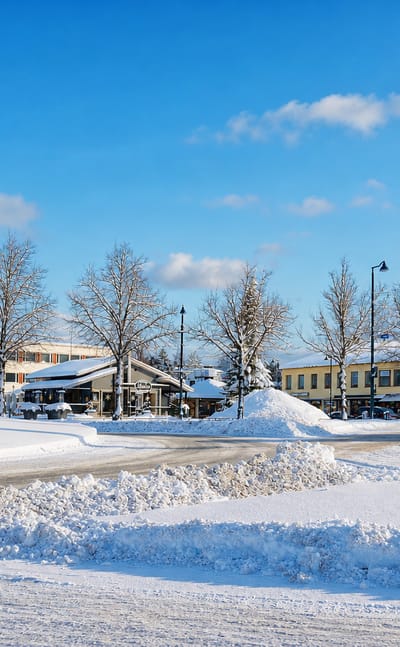 Snowy town centre of Jämsä, Finland, with low buildings, bare frosted trees and a cleared road under a blue winter sky.
