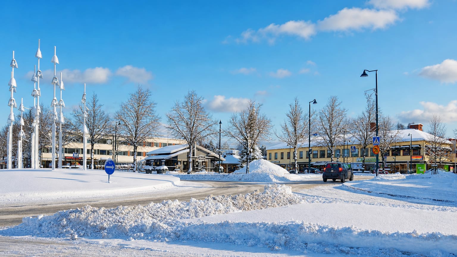 Snowy town centre of Jämsä, Finland, with low buildings, bare frosted trees and a cleared road under a blue winter sky.
