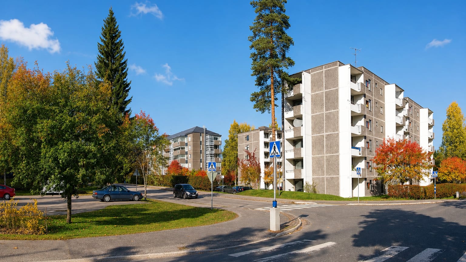 Autumn daytime view of Huhtasuo, a Jyväskylä suburb, with concrete apartment blocks and a roundabout among colourful trees.