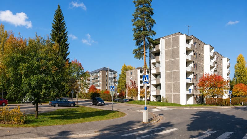 Autumn daytime view of Huhtasuo, a Jyväskylä suburb, with concrete apartment blocks and a roundabout among colourful trees.