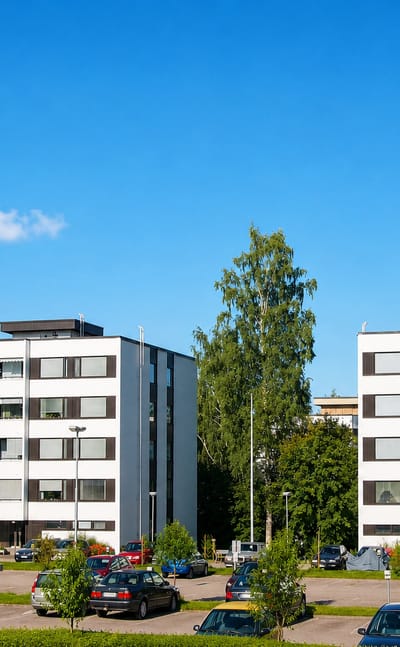 White apartment blocks and a car park among birches in Kortepohja, Jyvaskyla.