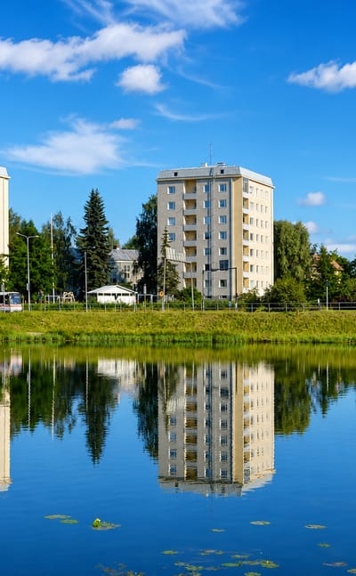 Apartment blocks mirrored in a still pond fringed with birches at Mattilanpelto in Jyväskylä.