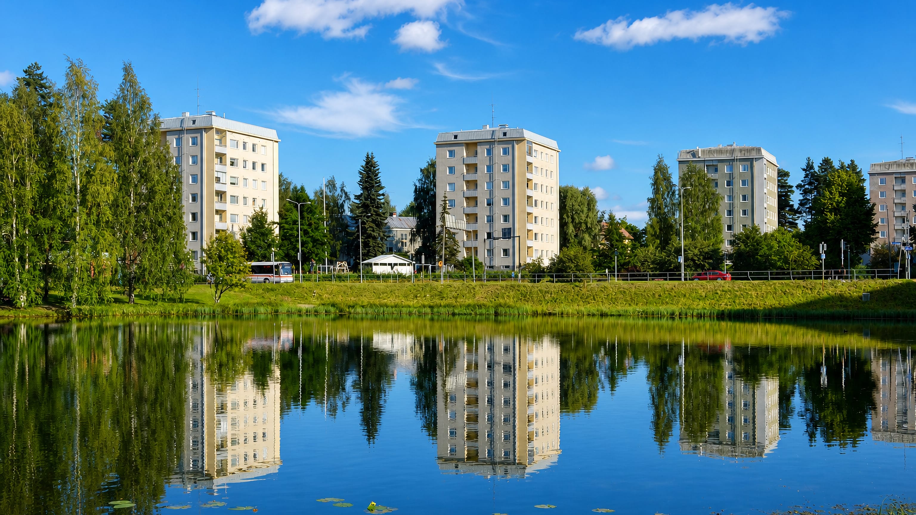 Apartment blocks mirrored in a still pond fringed with birches at Mattilanpelto in Jyväskylä.