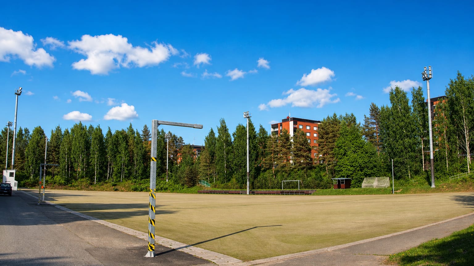 A floodlit sports field backed by pines and red-brick apartment blocks in Viitaniemi, Jyvaskyla.