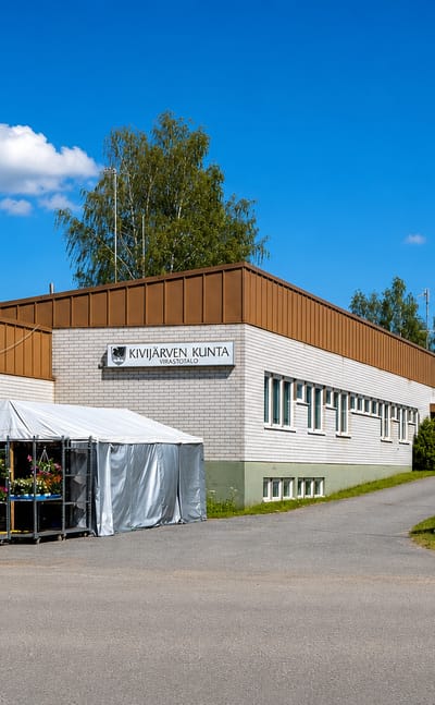 The Kivijärvi municipal office with a summer flower stall and parked cars, Finland.