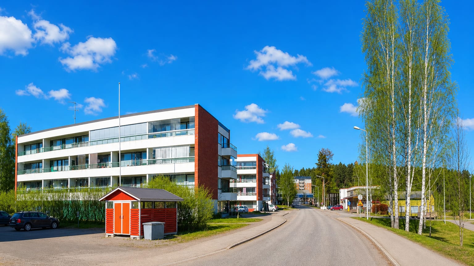 Residential street lined with modern apartment blocks and birch trees in Laukaa, Finland.