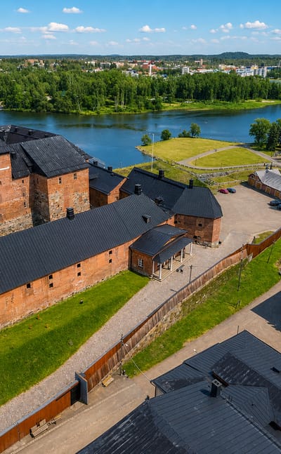 Aerial view of the red-brick medieval Häme Castle beside the lake with the town beyond in Hämeenlinna, Finland.