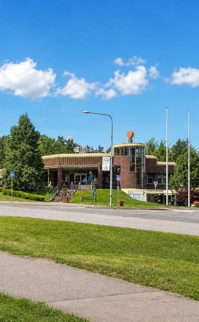 Loppi village centre with its church tower and modern brick community building across a junction, Finland.