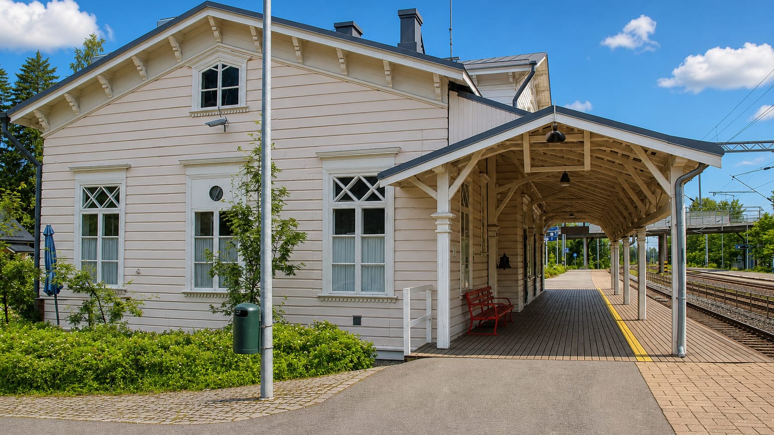 Historic cream wooden railway station with a covered platform and red bench in Turenki, Finland.