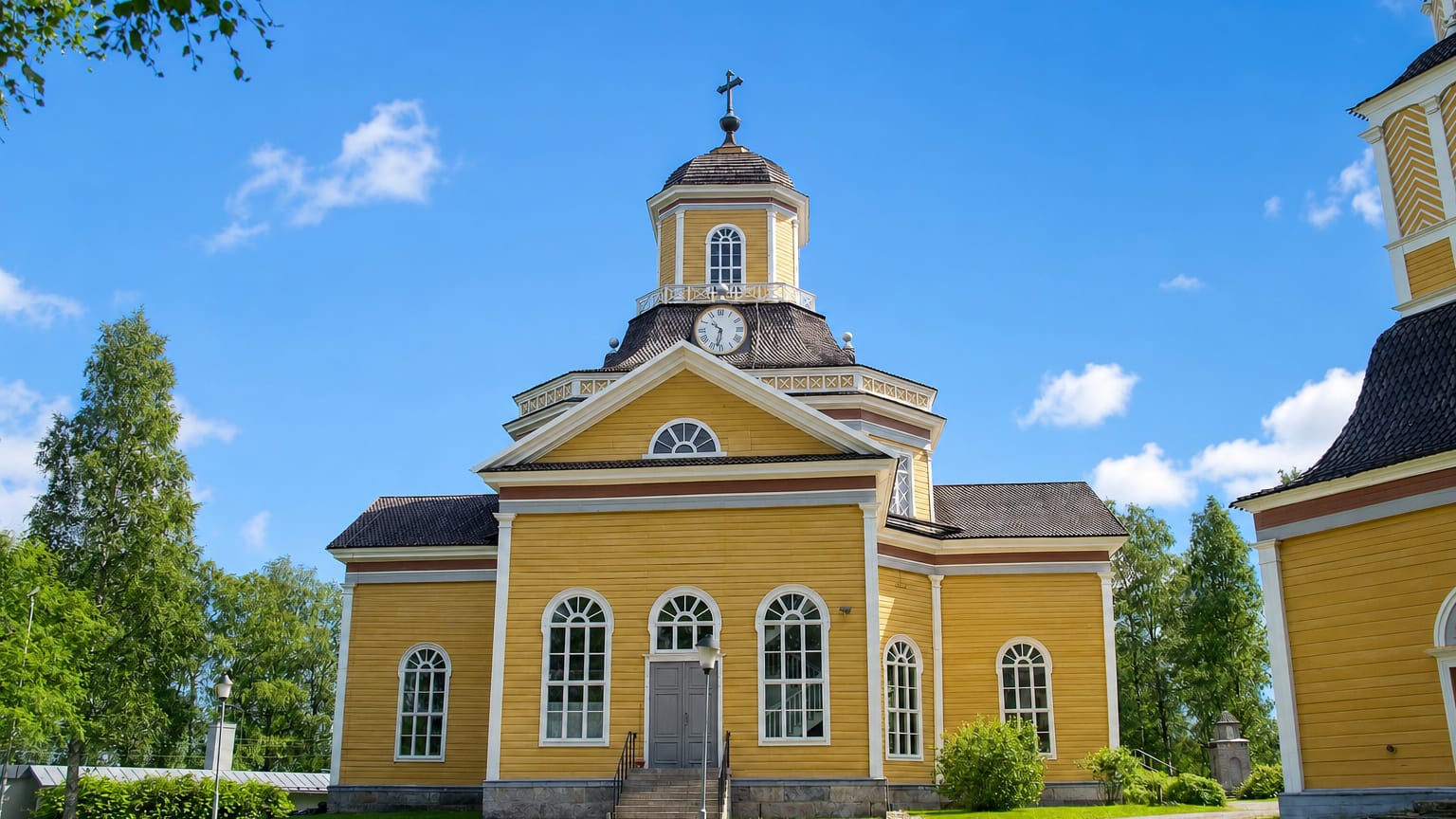 Yellow wooden church with a clock-topped lantern dome under blue sky in Kaustinen, Finland