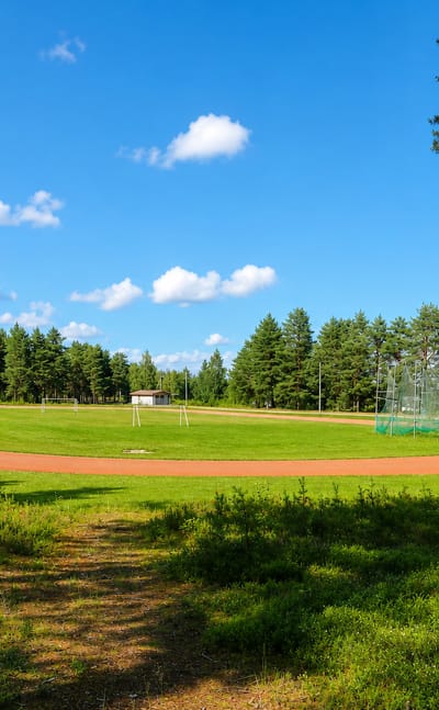Running track and sports field beside a lake ringed by pine forest in Lestijärvi, Finland.