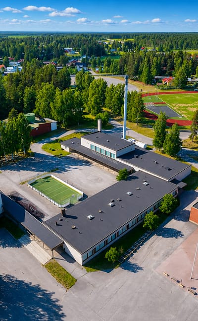 Aerial view of Veteli town centre in Central Ostrobothnia, Finland, with a school complex, running track and football pitch amid fields and forest