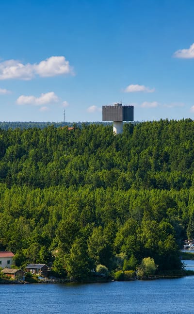 Forested ridge and water tower above waterfront houses and a boat marina at Karhuvuori in Kotka, Finland.