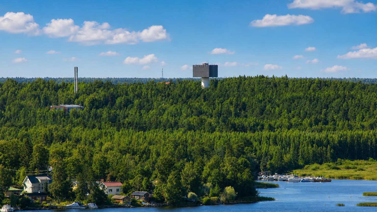 Forested ridge and water tower above waterfront houses and a boat marina at Karhuvuori in Kotka, Finland.