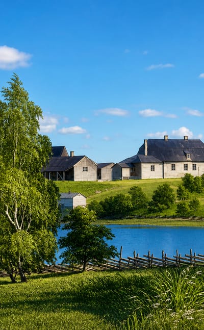 Lakeside summer view of a traditional grey manor house and rustic split-rail fence in rural Iitti, Finland.