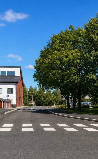 Quiet street crossing by a white civic building with road signs in Järvelä, Päijät-Häme, Finland