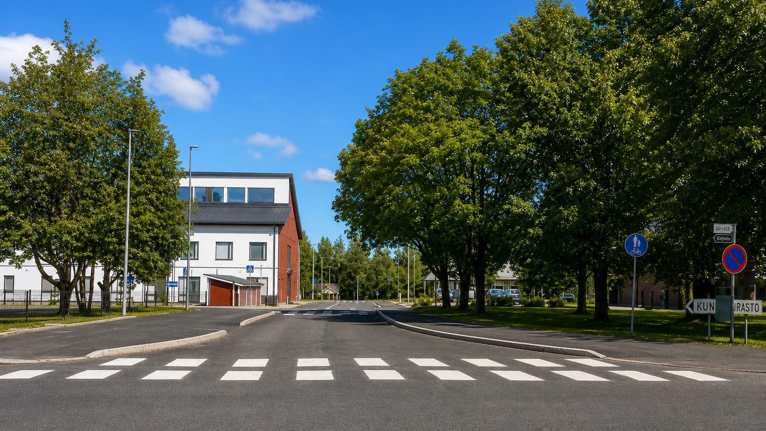 Quiet street crossing by a white civic building with road signs in Järvelä, Päijät-Häme, Finland