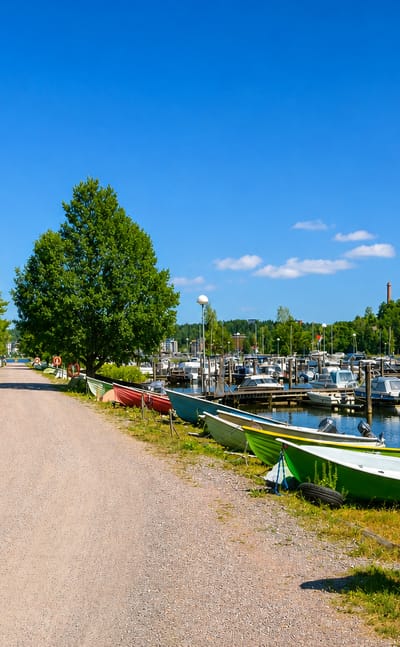 Rowing boats and a marina along the lakeside gravel path at Kartano in Lahti, Finland.