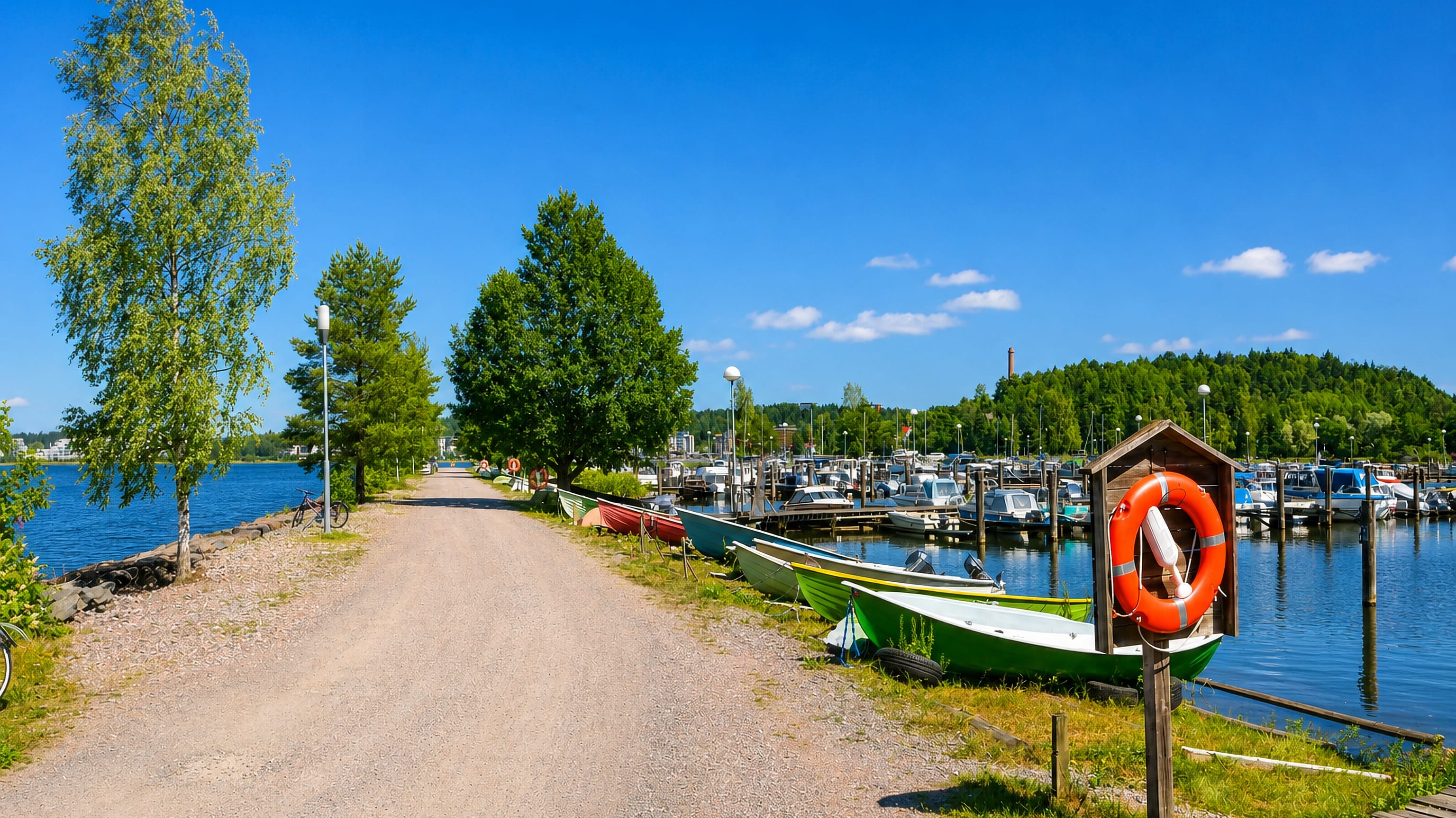 Rowing boats and a marina along the lakeside gravel path at Kartano in Lahti, Finland.