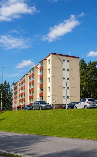 Beige and red 1970s apartment blocks among pines on a grassy slope in Liipola, Lahti.