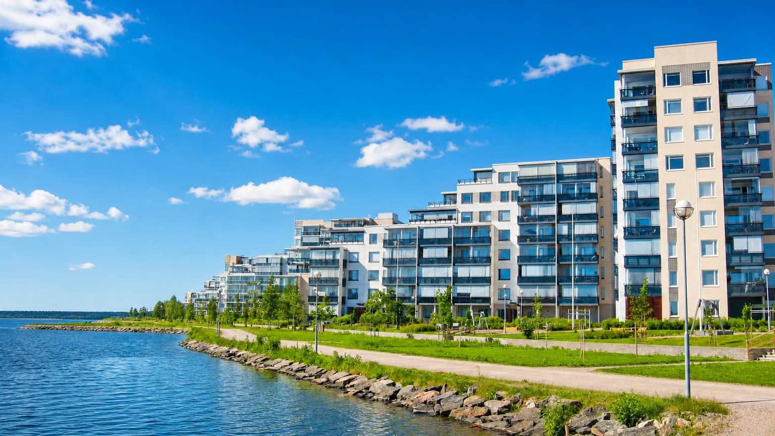Modern lakeside apartment buildings along the Vesijärvi waterfront in Niemi, Lahti, Finland, under a clear blue sky