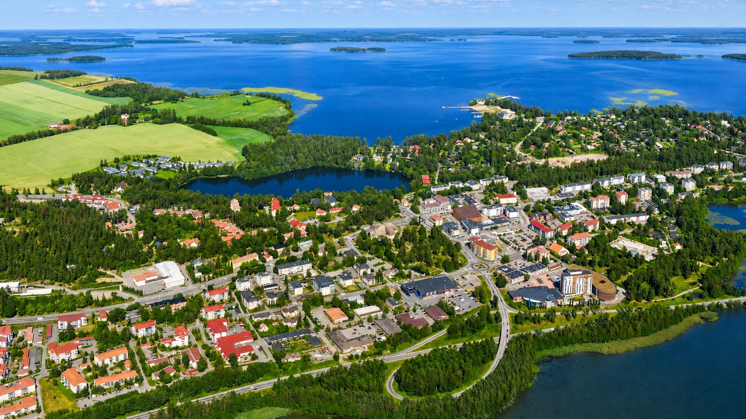 Aerial view of Kangasala town center in Finland, low-rise buildings and a church ringed by forests and blue lakes