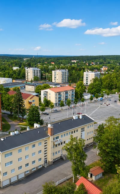 Aerial view of Toijala, Finland, showing its white-towered wooden church, yellow apartment blocks and surrounding forest.