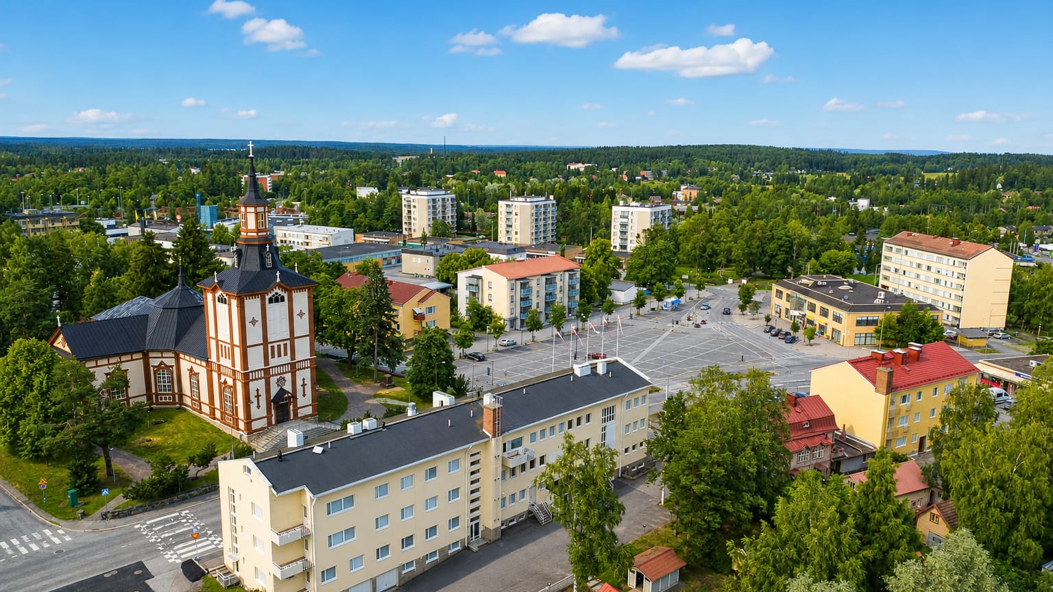 Aerial view of Toijala, Finland, showing its white-towered wooden church, yellow apartment blocks and surrounding forest.