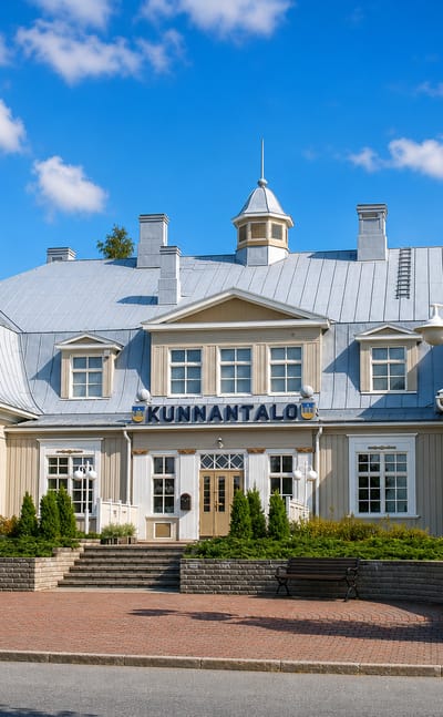 Cream-coloured Kunnantalo municipal hall framed by red rowan trees in Punkalaidun, Finland.