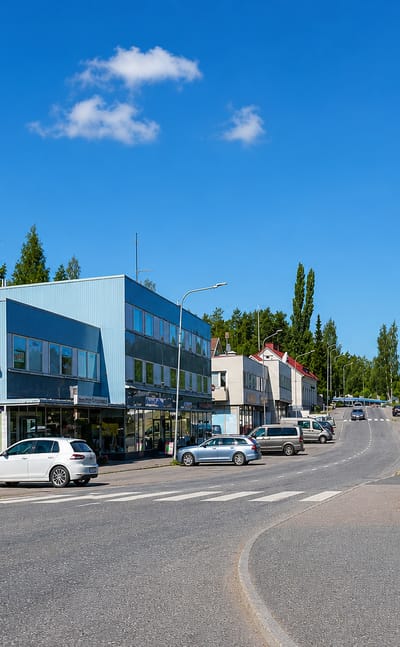 Sunlit main street with shops and a red timber house in Ruovesi, Finland.