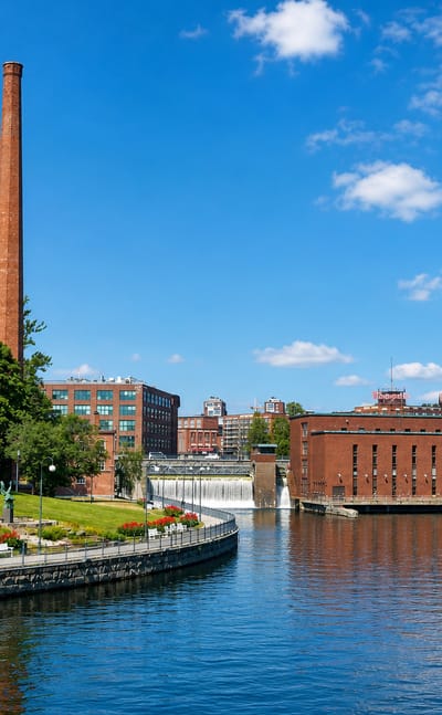 Tampere's red-brick industrial mills and tall chimney along the Tammerkoski rapids under a clear summer sky