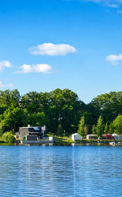 Wooded lakeshore with small boats moored below the trees at Kaakinmaa in Tampere.