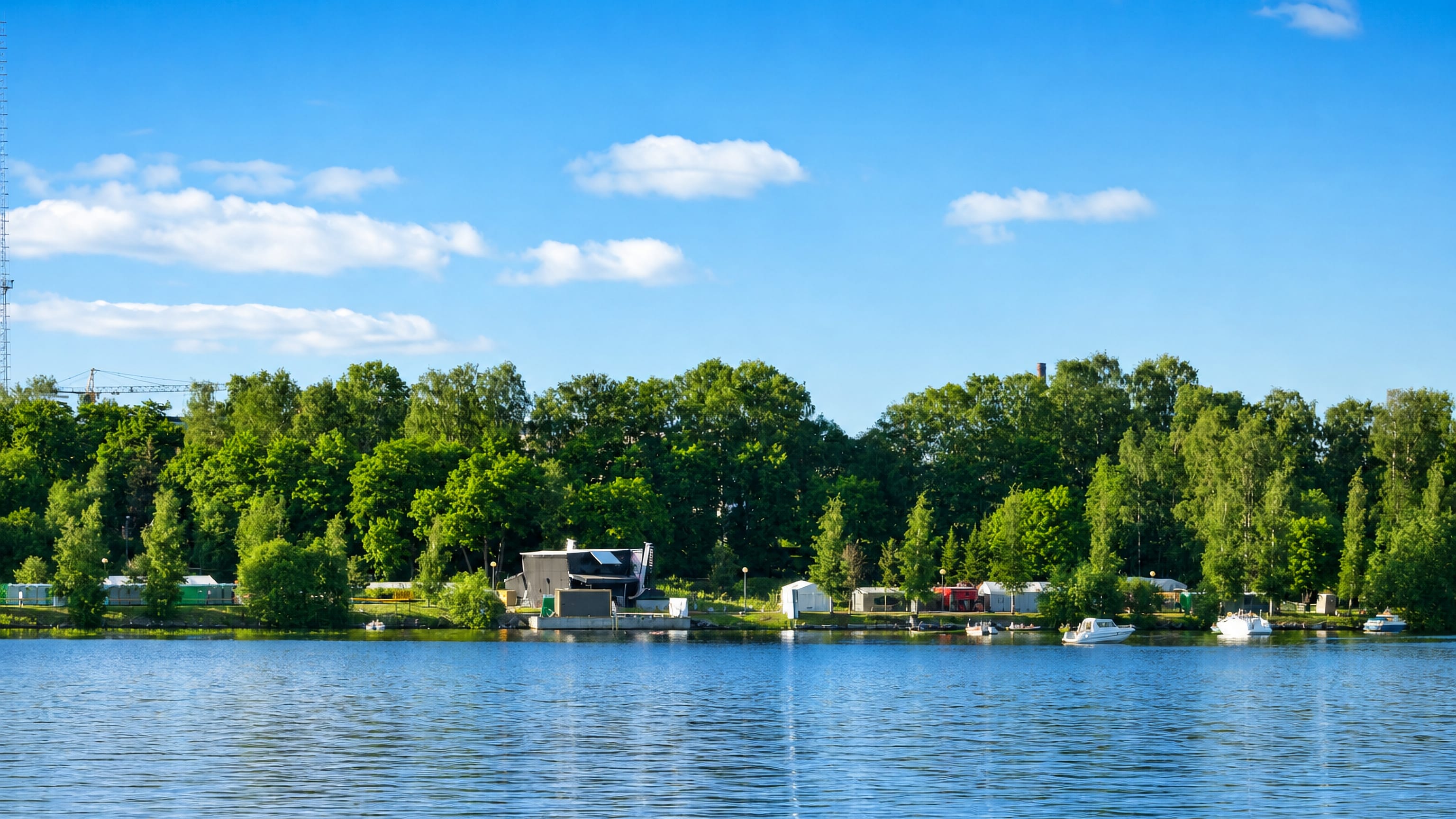 Wooded lakeshore with small boats moored below the trees at Kaakinmaa in Tampere.