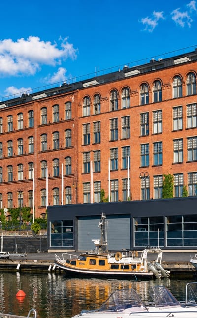 Red-brick former cotton mill and its tower rising above the lakeside marina at Lapinniemi, Tampere.