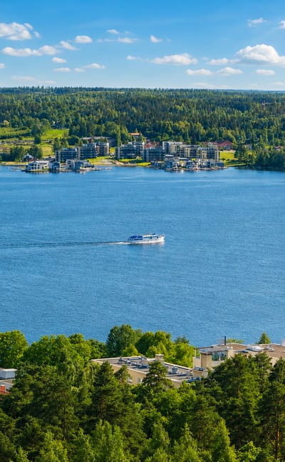 Pyynikki ridge in Tampere above Pyhajarvi lake, with a tall brick factory chimney and a passing boat.