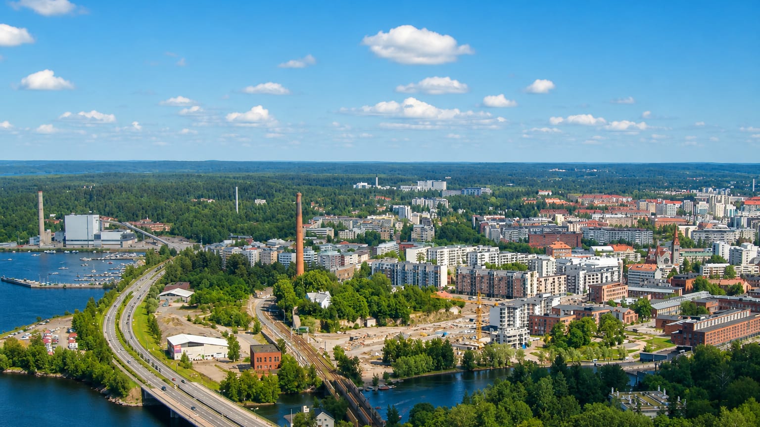 Aerial daytime view of Tampella, Tampere, with its red-brick factory chimney, lakeside waterfront and modern apartment blocks.
